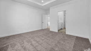 Unfurnished bedroom featuring recessed lighting, baseboards, ensuite bathroom, and light carpet