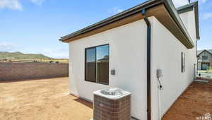 Exterior space featuring stucco siding, central AC unit, a mountain view, and fence