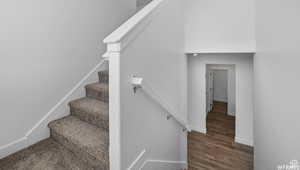 Stairway with wood finished floors and baseboards