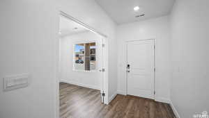 Foyer entrance with recessed lighting, visible vents, baseboards, and wood finished floors