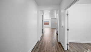 Hallway with dark wood-type flooring and baseboards