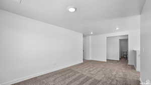 Carpeted spare room with baseboards and a textured ceiling