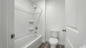 Full bathroom with shower / bathing tub combination, baseboards, toilet, and wood finished floors