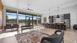 Living room with light wood-style flooring, a ceiling fan, visible vents, and baseboards