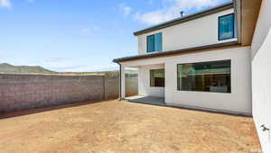 Rear view of house with stucco siding, a patio, and fence