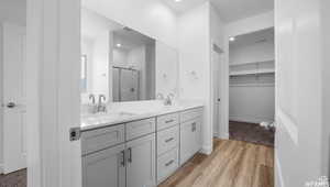 Bathroom with a sink, double vanity, wood finished floors, and a shower stall