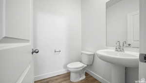 Bathroom with toilet, wood finished floors, and baseboards