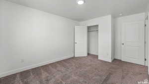 Unfurnished bedroom featuring carpet flooring, baseboards, and a closet