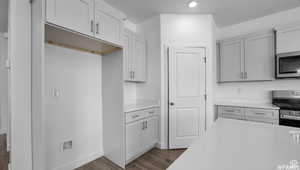 Kitchen featuring dark wood finished floors, light countertops, baseboards, and appliances with stainless steel finishes