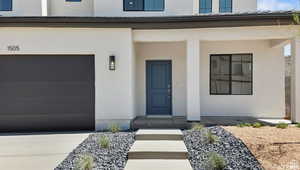 Entrance to property featuring stucco siding, driveway, and a garage