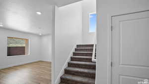 Stairs with recessed lighting, baseboards, a textured ceiling, and wood finished floors