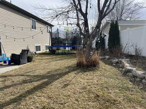 View of yard featuring a trampoline and fence