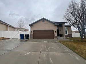 Ranch-style house with an attached garage, a gate, brick siding, and driveway