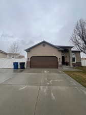 View of front of house featuring brick siding, fence, concrete driveway, an attached garage, and a gate