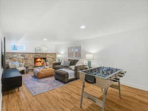 Living room featuring recessed lighting, baseboards, a stone fireplace, and wood finished floors