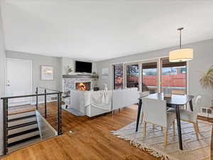 Dining area with a tiled fireplace, wood finished floors, and visible vents