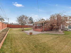 View of yard with a deck, a patio area, a fenced backyard, and a fire pit