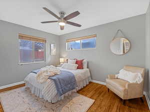 Bedroom featuring multiple windows, ceiling fan, baseboards, and wood finished floors