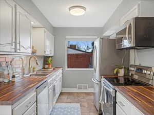 Kitchen featuring visible vents, appliances with stainless steel finishes, wood counters, and a sink