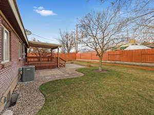 View of yard featuring a patio, central air condition unit, a fenced backyard, and a wooden deck