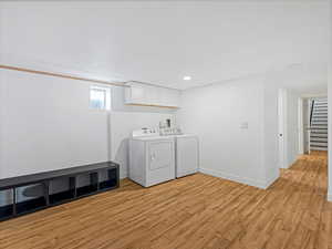 Laundry area featuring light wood-type flooring, independent washer and dryer, recessed lighting, cabinet space, and baseboards