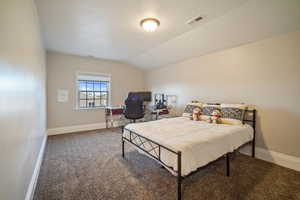 Carpeted bedroom with visible vents, a textured ceiling, baseboards, and vaulted ceiling