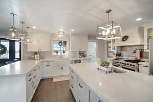 Kitchen with a sink, custom exhaust hood, a peninsula, and white cabinets