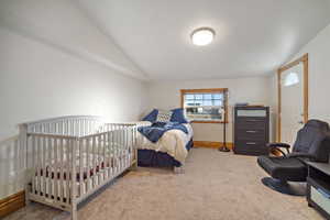 Carpeted bedroom with lofted ceiling and baseboards