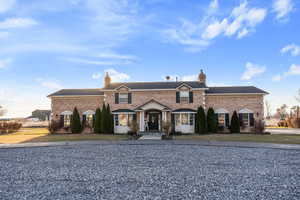 View of front of house featuring brick siding, a chimney, and a front yard