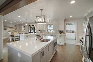 Kitchen featuring light countertops, recessed lighting, dark wood-style floors, stainless steel appliances, and a sink