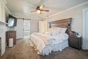 Bedroom featuring a barn door, crown molding, visible vents, and carpet floors