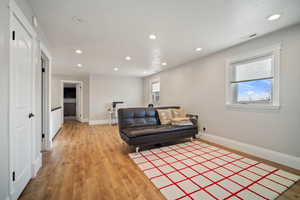 Living area featuring recessed lighting, visible vents, light wood-style flooring, and baseboards