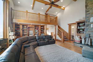 Living area with beam ceiling, stairway, high vaulted ceiling, and wood finished floors