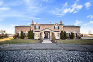 View of front facade featuring a front yard, brick siding, and a chimney