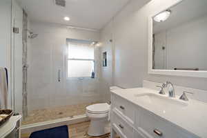 Full bathroom with visible vents, a shower stall, toilet, wood finished floors, and vanity