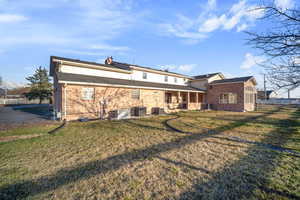 Back of house with a patio, central AC unit, fence, a lawn, and brick siding