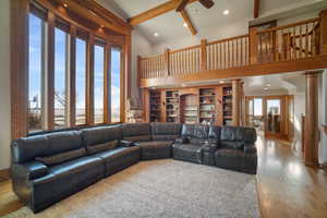 Living room with beam ceiling, decorative columns, wood finished floors, and a wealth of natural light