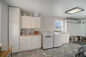 Clothes washing area featuring washer and dryer and cabinet space