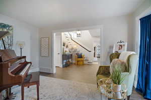 Living area featuring visible vents, baseboards, wood finished floors, and stairs