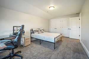 Carpeted bedroom with visible vents, baseboards, a textured ceiling, and vaulted ceiling