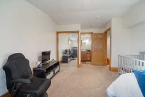 Bedroom featuring lofted ceiling, baseboards, and light carpet