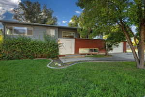 View of front of property featuring a front yard, an attached garage, brick siding, and driveway