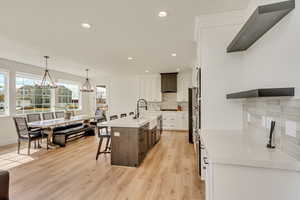 Kitchen featuring a center island with sink, a breakfast bar, light wood-type flooring, light countertops, and a sink