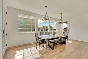 Dining room with baseboards, light wood-style floors, and a chandelier