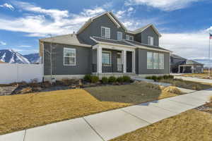 View of front of property with a mountain view, a porch, a front yard, and fence