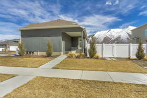 View of front of home with stucco siding, a front lawn, a gate, fence, and a mountain view