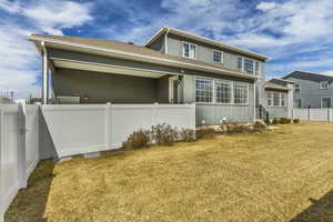 Back of house with stucco siding, a lawn, and fence