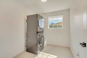 Laundry area with laundry area, stacked washing maching and dryer, and baseboards