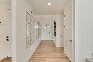 Corridor with light wood finished floors, stairway, and baseboards