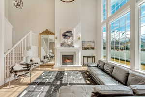 Living room with a fireplace, stairway, wood finished floors, and a towering ceiling